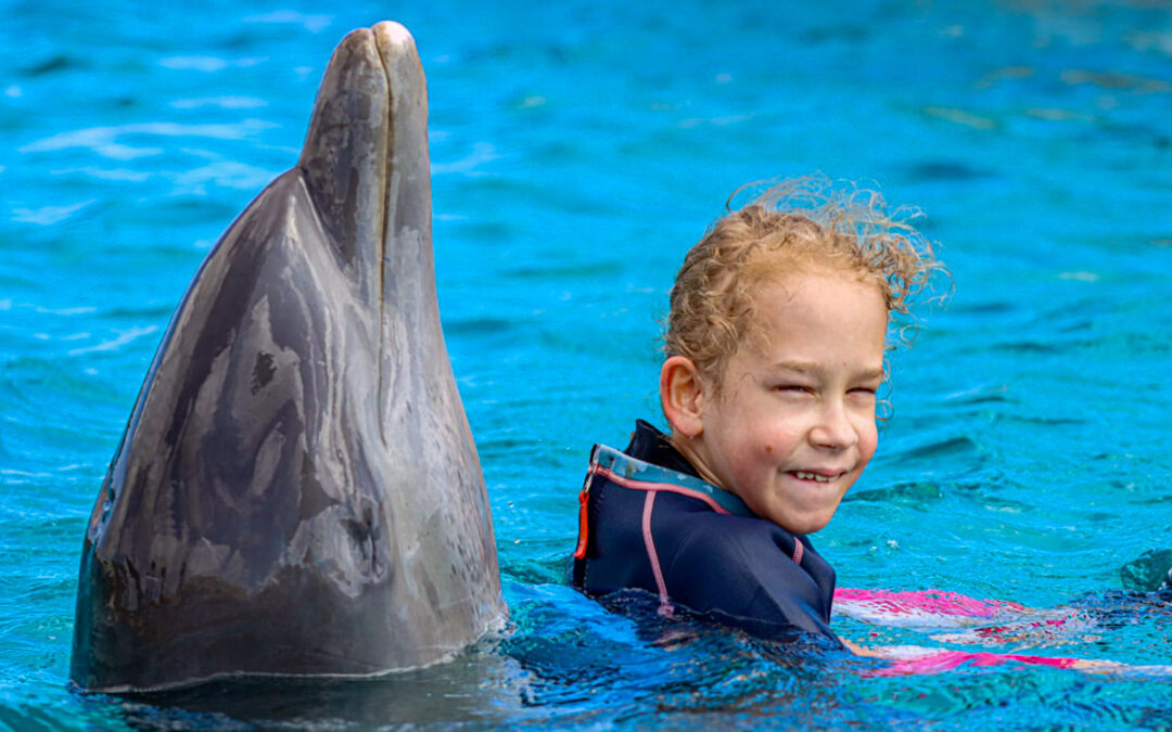 Sarah wird vom Delfin im Wasser gehalten